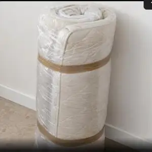 Vecchio materasso arrotolato e avvolto in plastica per lo smaltimento